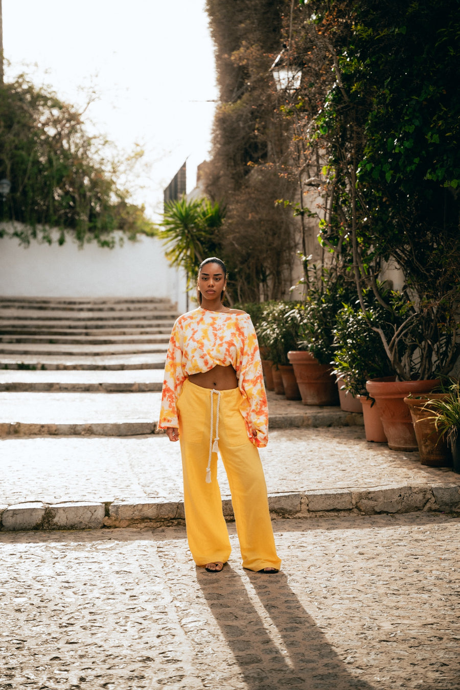 Modelo con top tie-dye Warm feel y pantalón amarillo All day pants en las calles de Ibiza